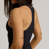 Woman wearing a black racerback against a plain background