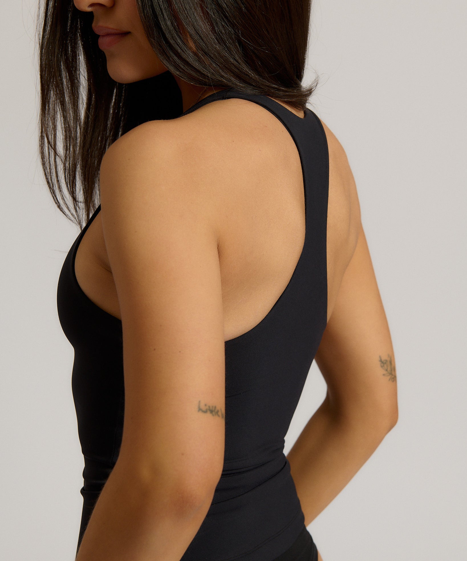 Woman wearing a black racerback against a plain background