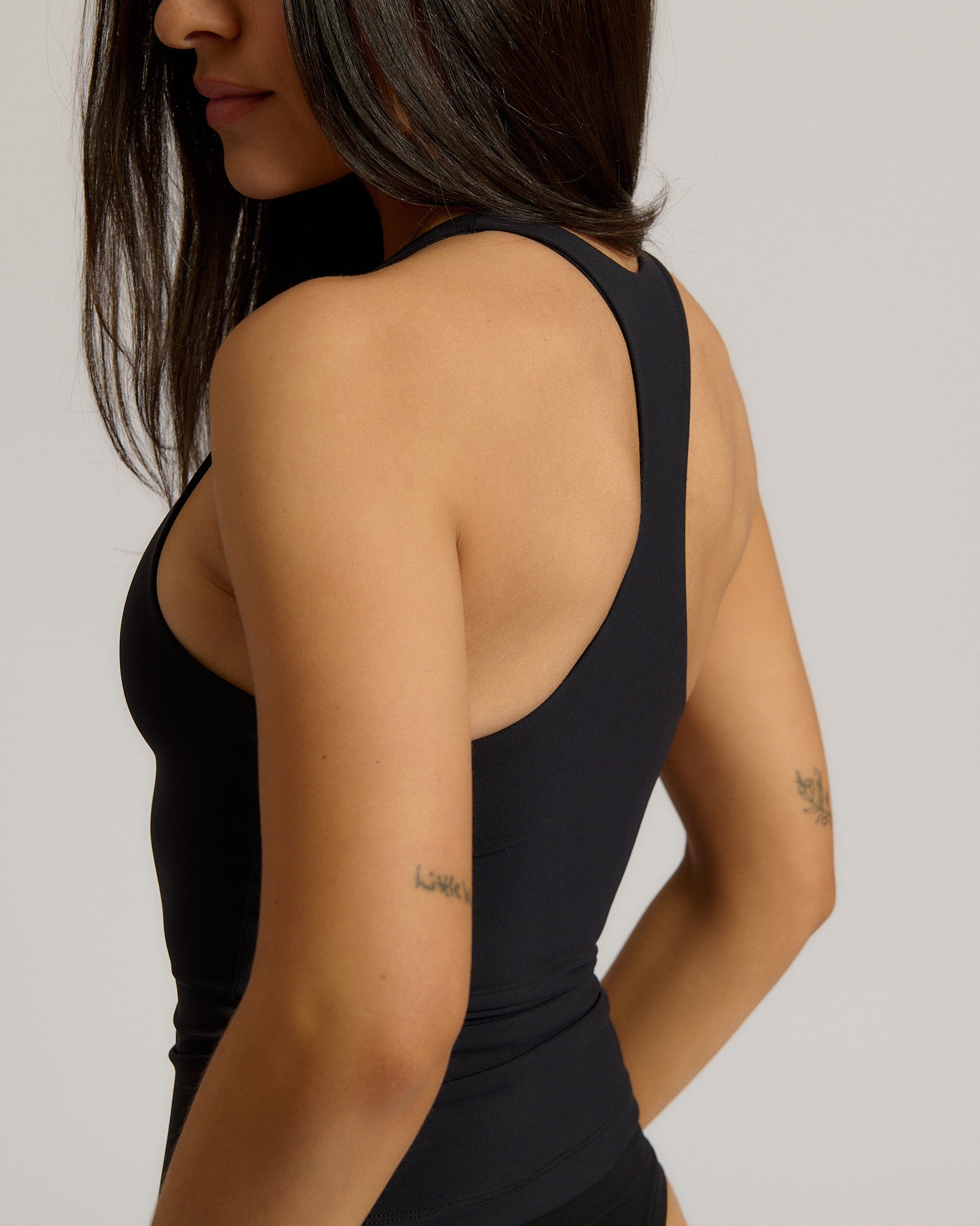 Woman wearing a black racerback against a plain background