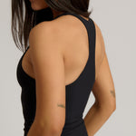 Woman wearing a black racerback against a plain background