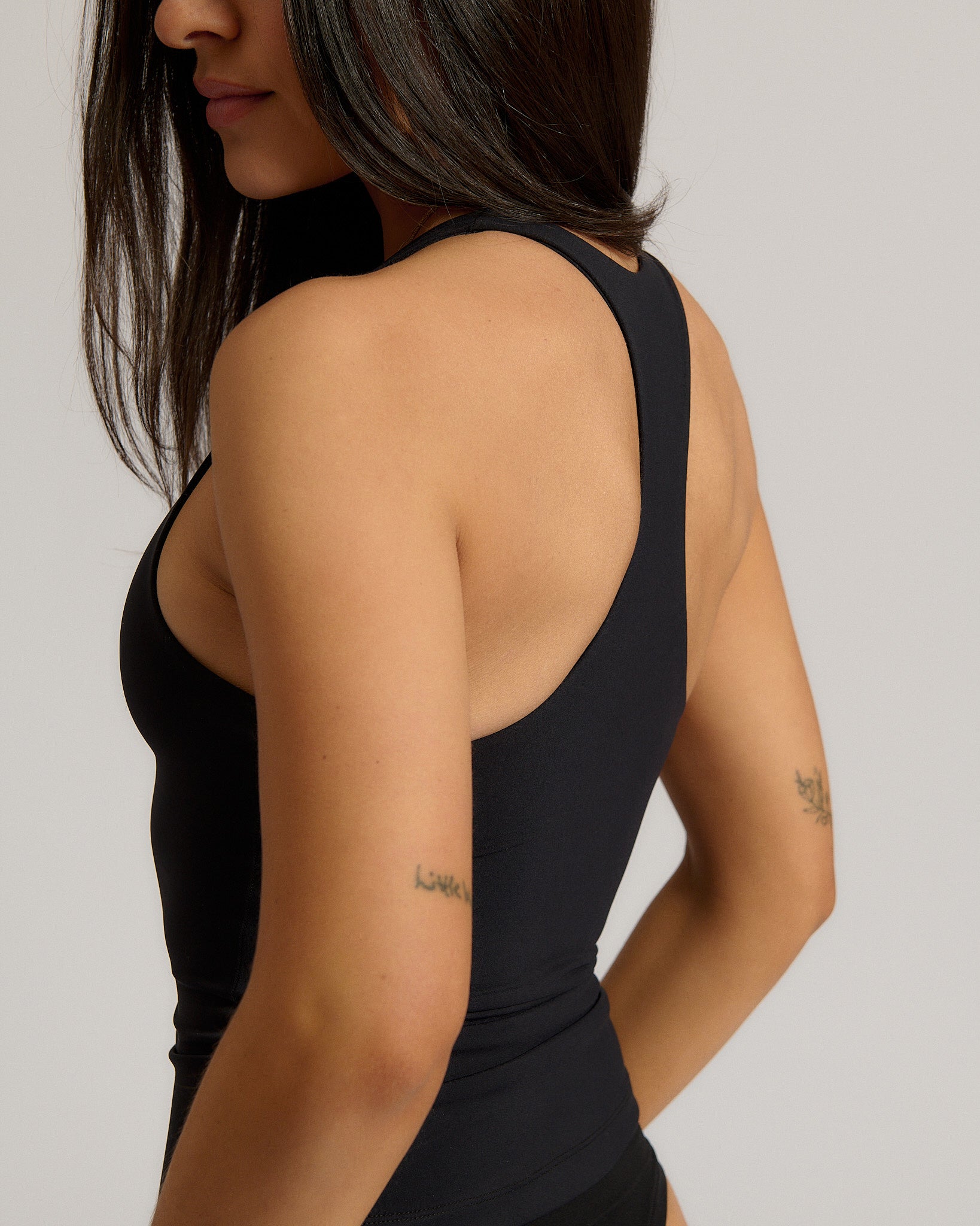 Woman wearing a black racerback against a plain background