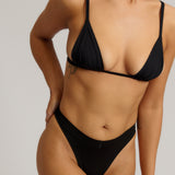Black triangle bra worn by a model on a plain background