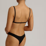 Black triangle bra worn by a model on a plain background