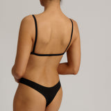 Black triangle bra worn by a model on a plain background