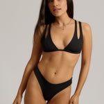 Woman wearing a black bikini against a plain background