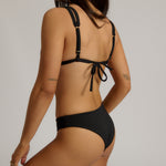 Woman wearing a black bikini with a plain background