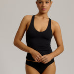 Woman wearing a black racerback against a plain background