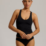 Woman wearing a black racerback against a plain background