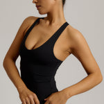 Woman wearing a black racerback against a plain background