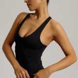 Woman wearing a black racerback against a plain background