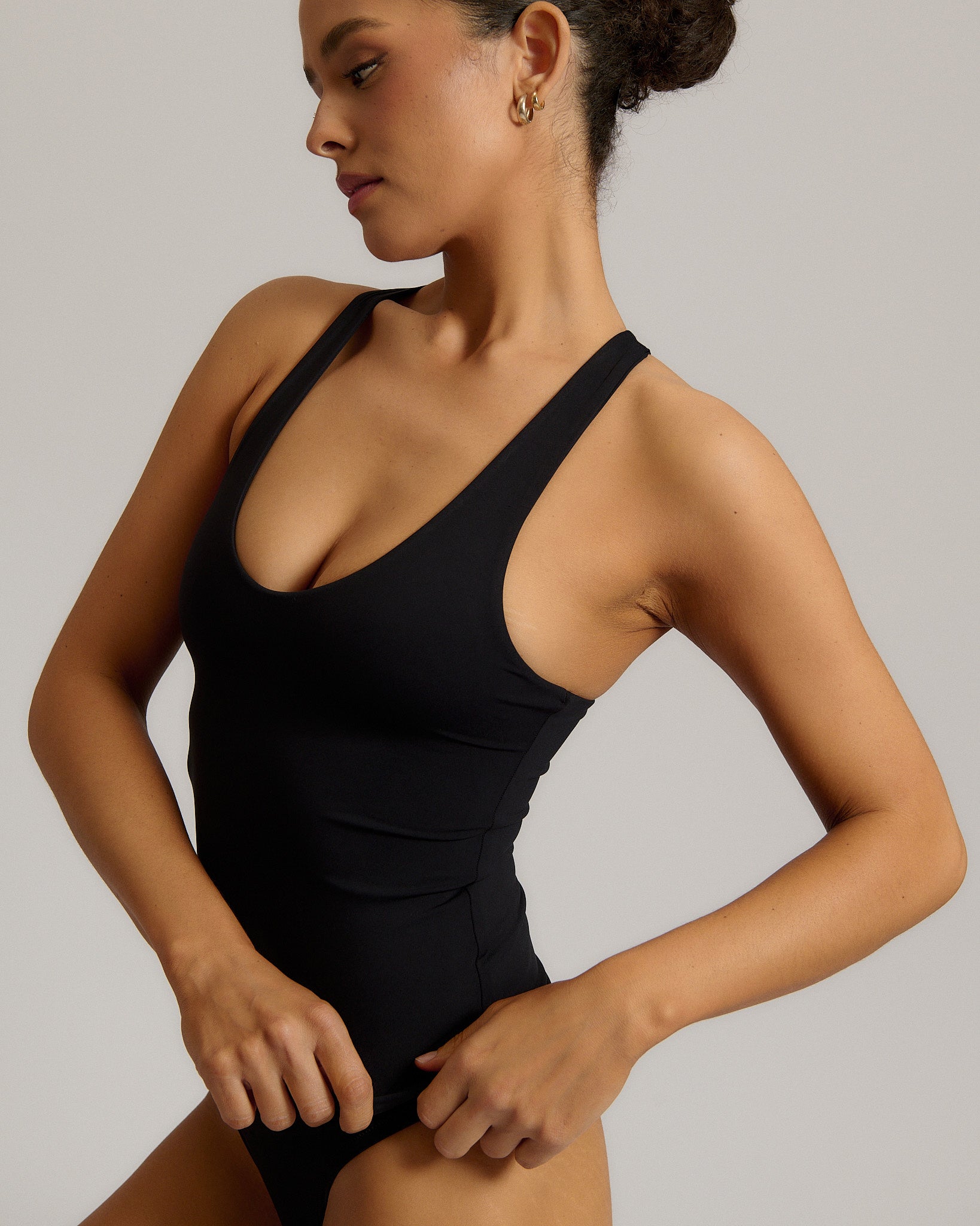 Woman wearing a black racerback against a plain background