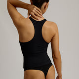 Woman wearing a black racerback against a plain background