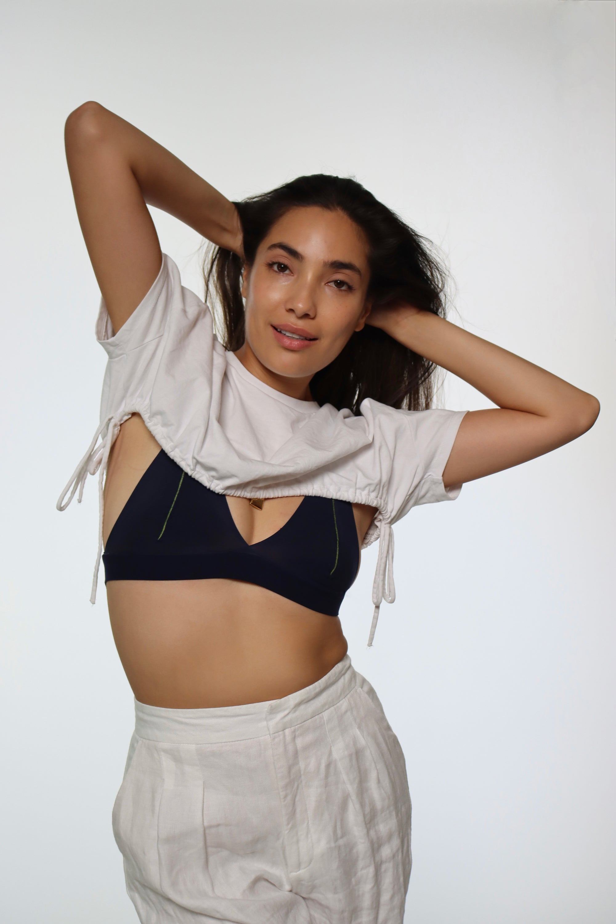 Woman standing wearing pants and a crop top in white and the Racerback System in Midnight
