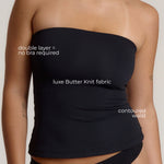 Woman wearing a black strapless top against a gray background