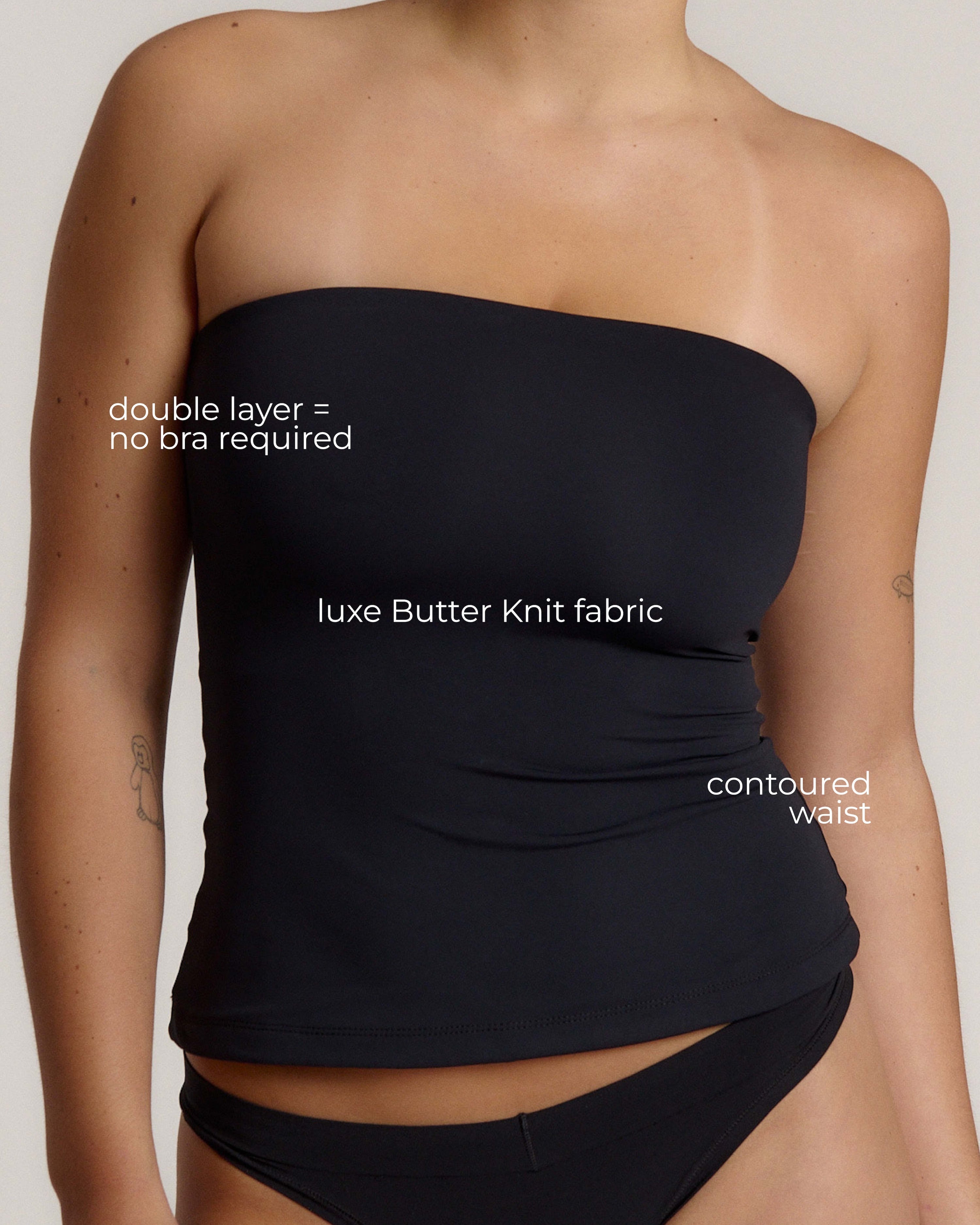 Woman wearing a black strapless top against a gray background