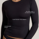 Woman wearing a black long-sleeve top and black bottom on a light gray background