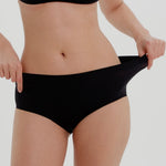 Person wearing black high-waisted underwear on a light gray background