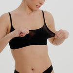 Person wearing a black cami system against a plain background