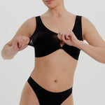 A woman is wearing a black twist system and thong