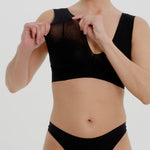 A woman wearing a black vii system with wide straps and a deep neckline.
