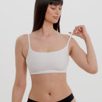 Woman wearing a white bra and white underwear on a plain background