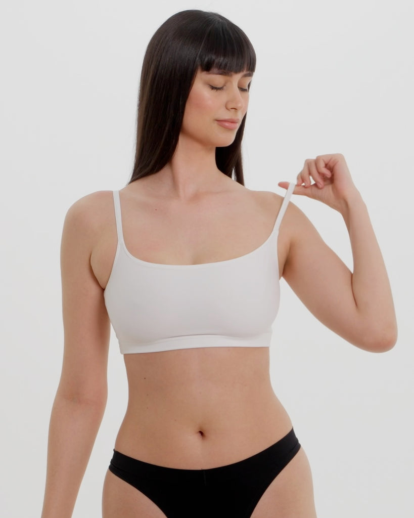 Woman wearing a white bra and white underwear on a plain background