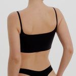 Person wearing a black bra and underwear on a plain background