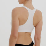 Woman wearing a white racerback on a plain background