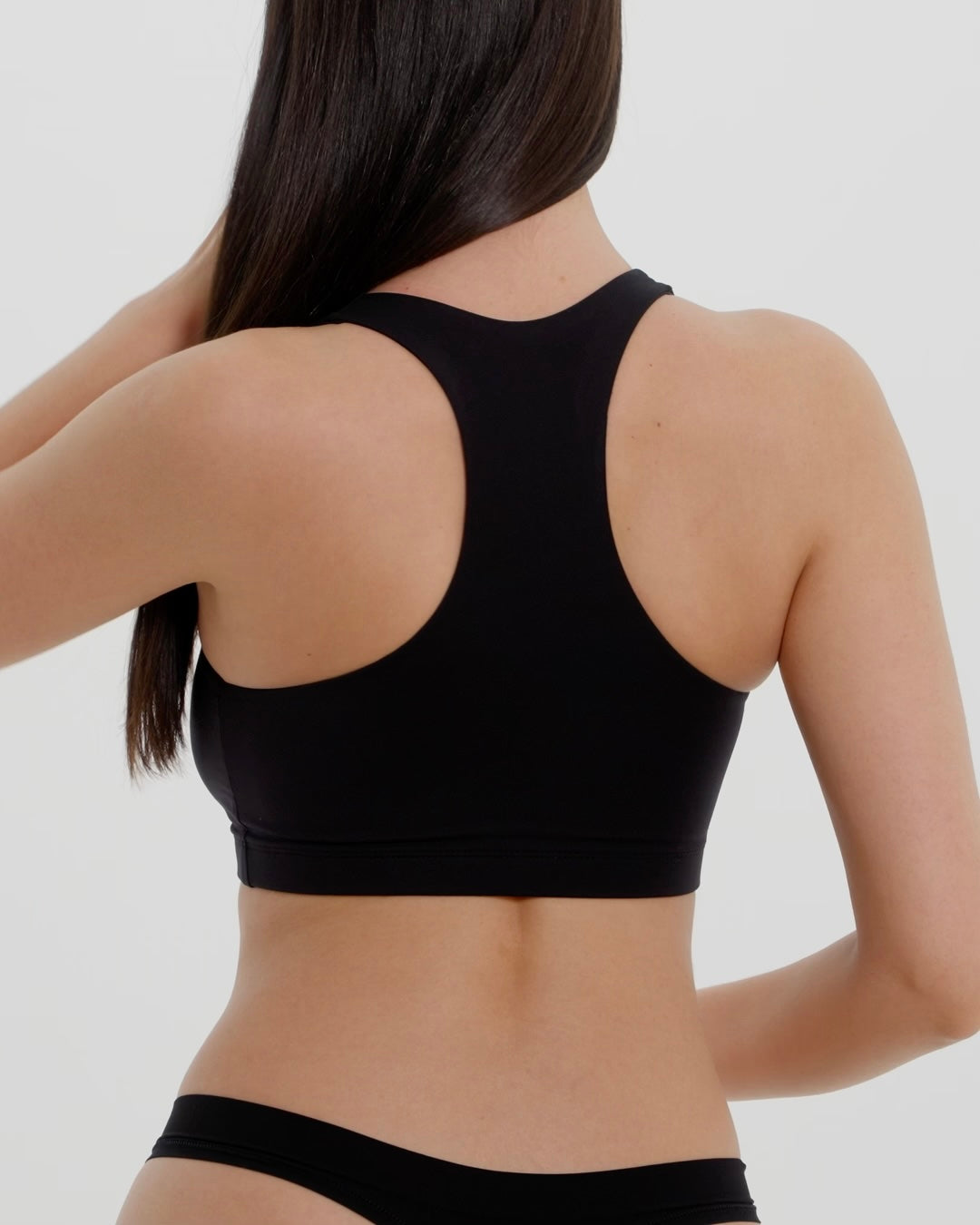 Woman wearing a black racerback on a plain background