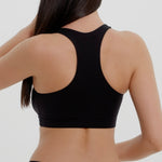 Woman wearing a black racerback on a plain background