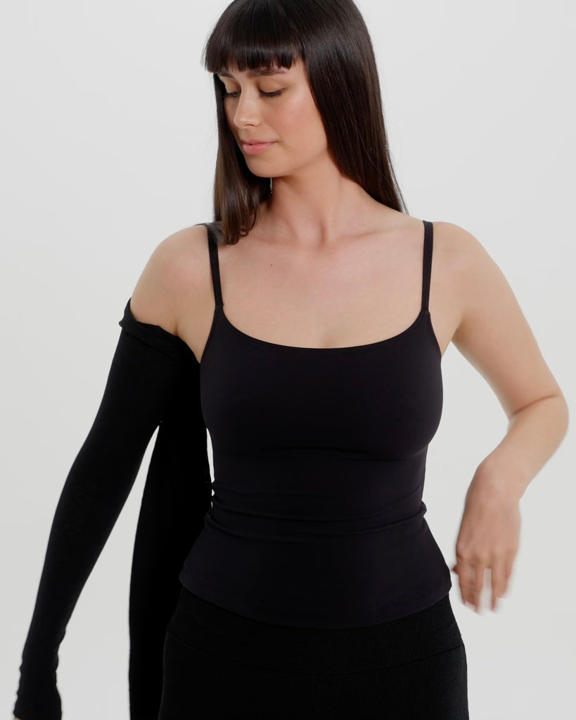 Person wearing a black bra and bolero on a plain background