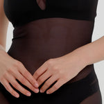 Woman wearing a black sheer dress against a plain background