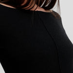 Black long-sleeve top worn by a person on a plain background