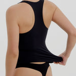 Woman wearing a black racerback against a plain background