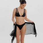 Black bikini with a tied sarong on a neutral background