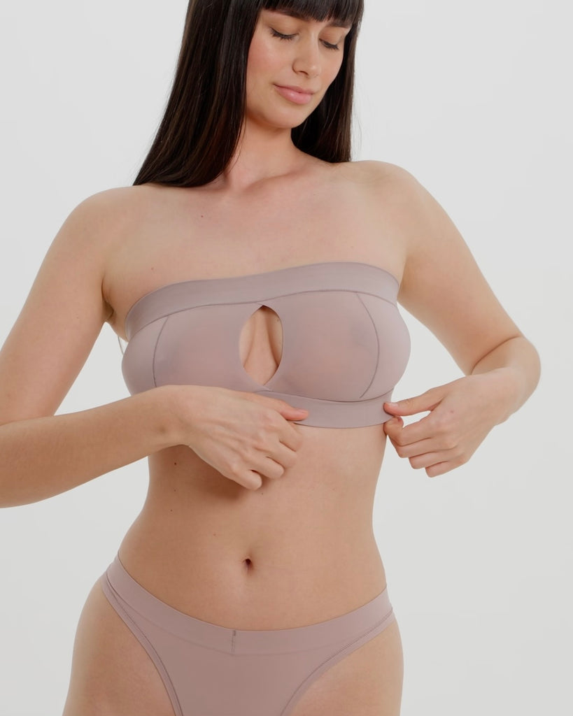 Woman wearing a beige strapless against a plain background