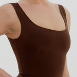 Woman wearing a brown tank top against a white background